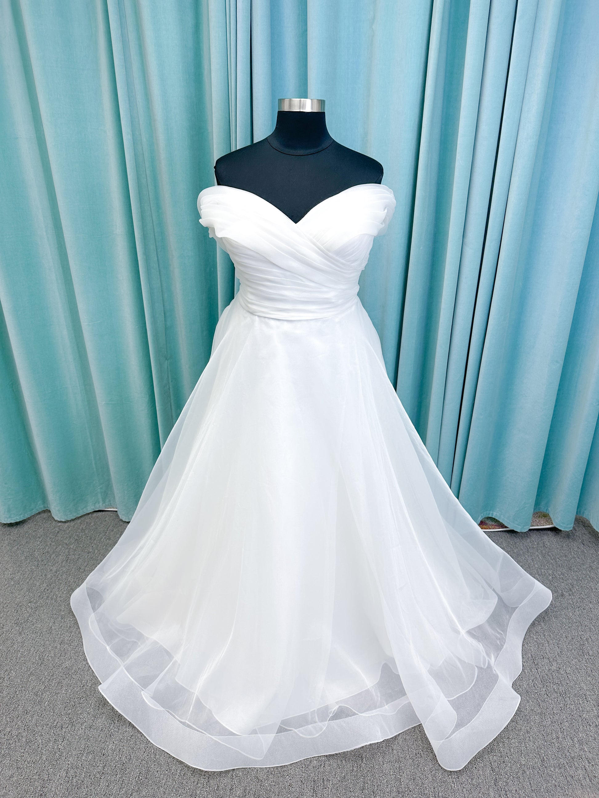 Morilee 3350 Evette ball gown wedding dress in draped organza with off-the-shoulder surplice bodice, horsehair-edged skirt, and covered buttons to hem.