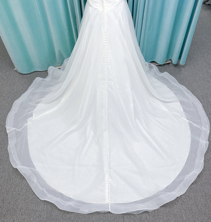 Morilee 3350 Evette ball gown wedding dress in draped organza with off-the-shoulder surplice bodice, horsehair-edged skirt, and covered buttons to hem.