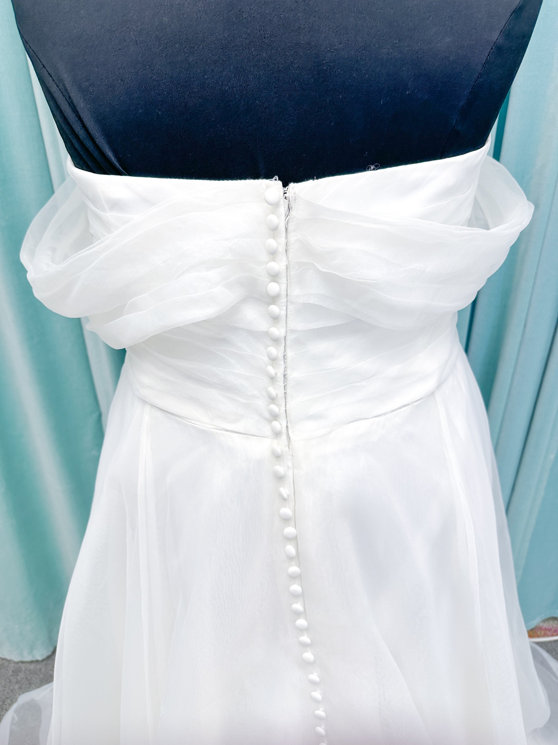 Morilee 3350 Evette ball gown wedding dress in draped organza with off-the-shoulder surplice bodice, horsehair-edged skirt, and covered buttons to hem.