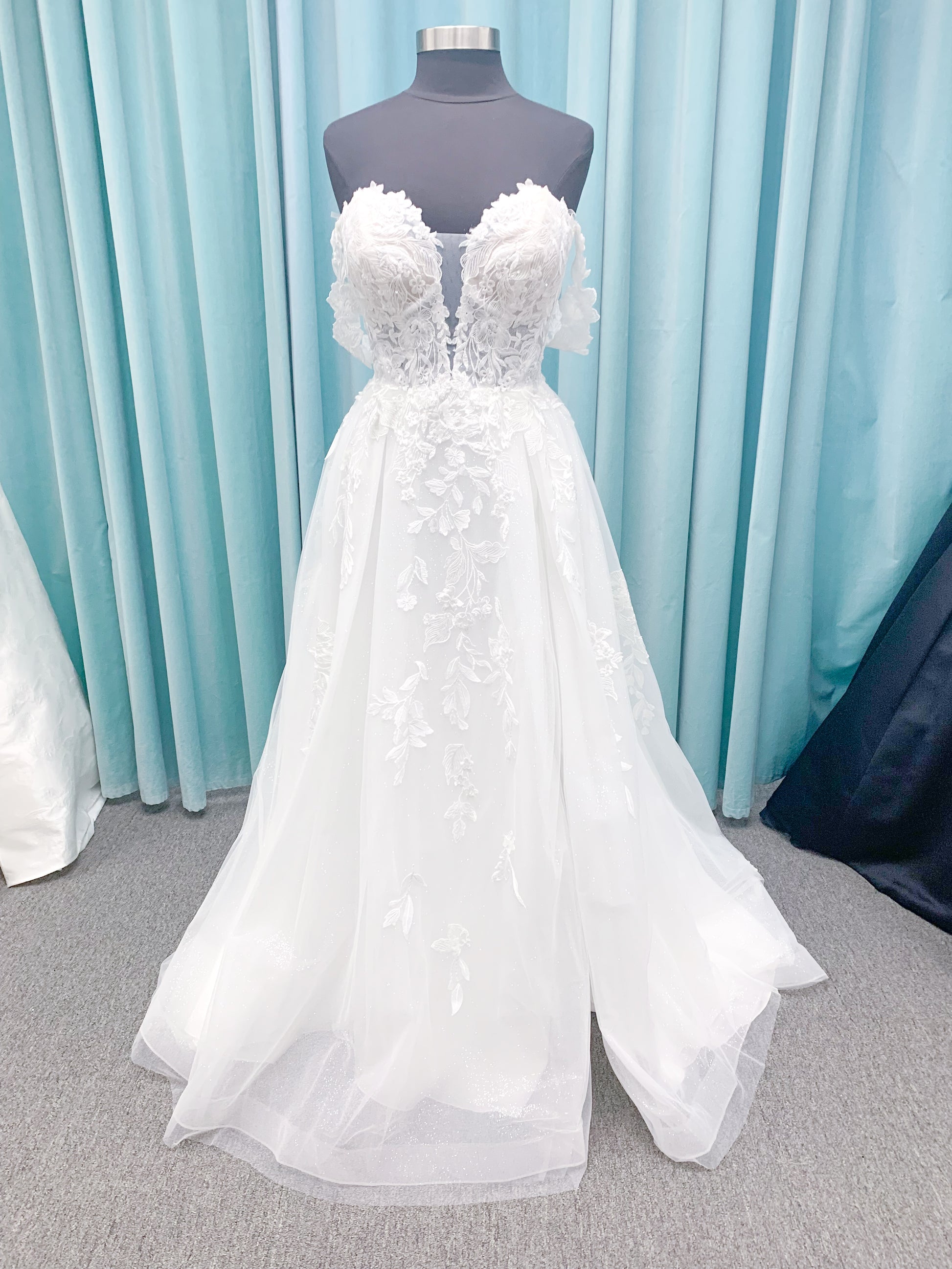 Morilee 2979 Filippa A-line wedding dress in glitter tulle with plunge sweetheart bodice, sequin beaded threadwork appliqués, detachable off-shoulder straps, and front slit.