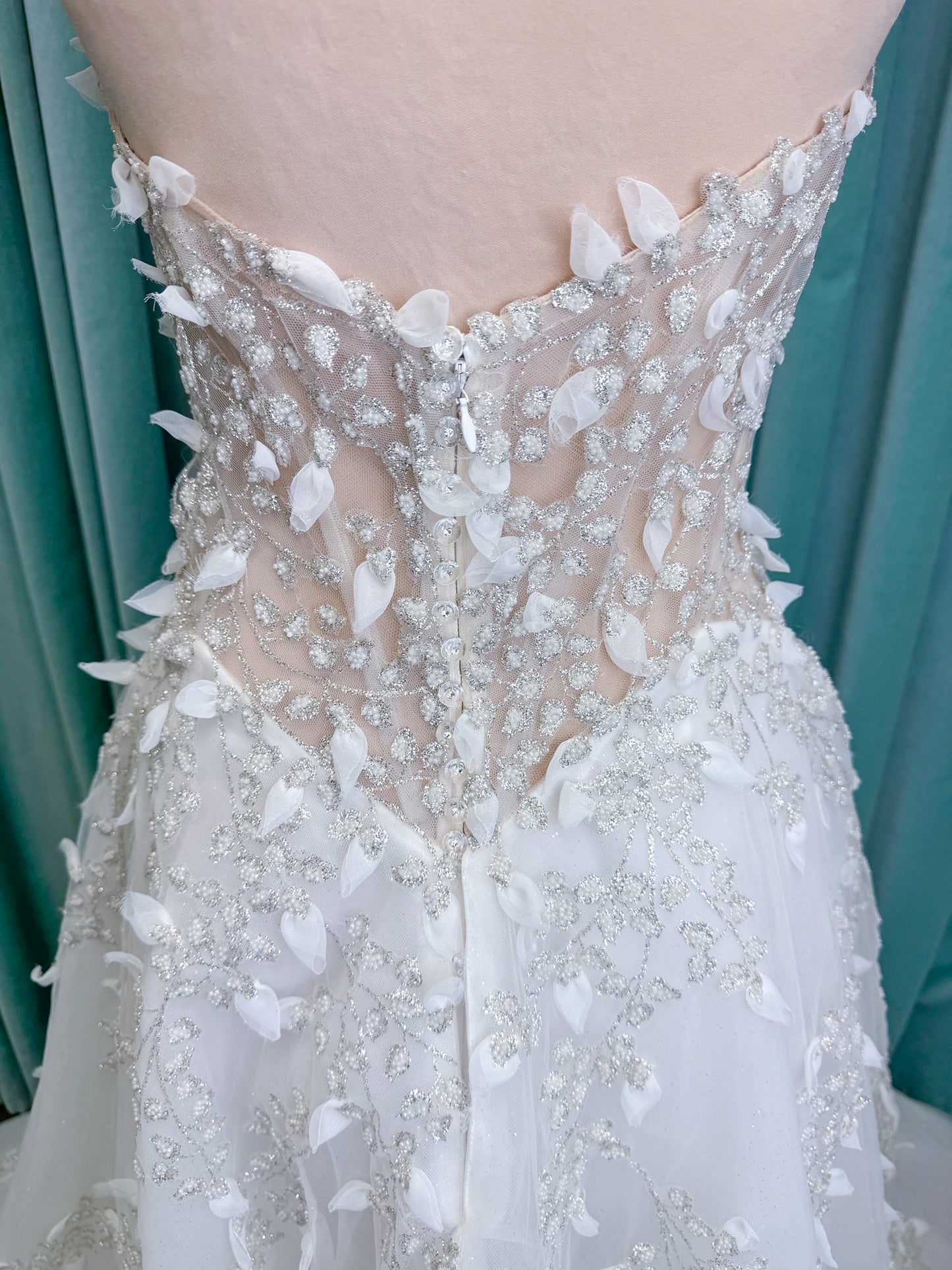 Randy Fenoli Goddess ballgown wedding dress on mannequin with plunging sweetheart neckline, 3D leaf appliqué, basque waist, high skirt slit, and sparkle tulle skirt