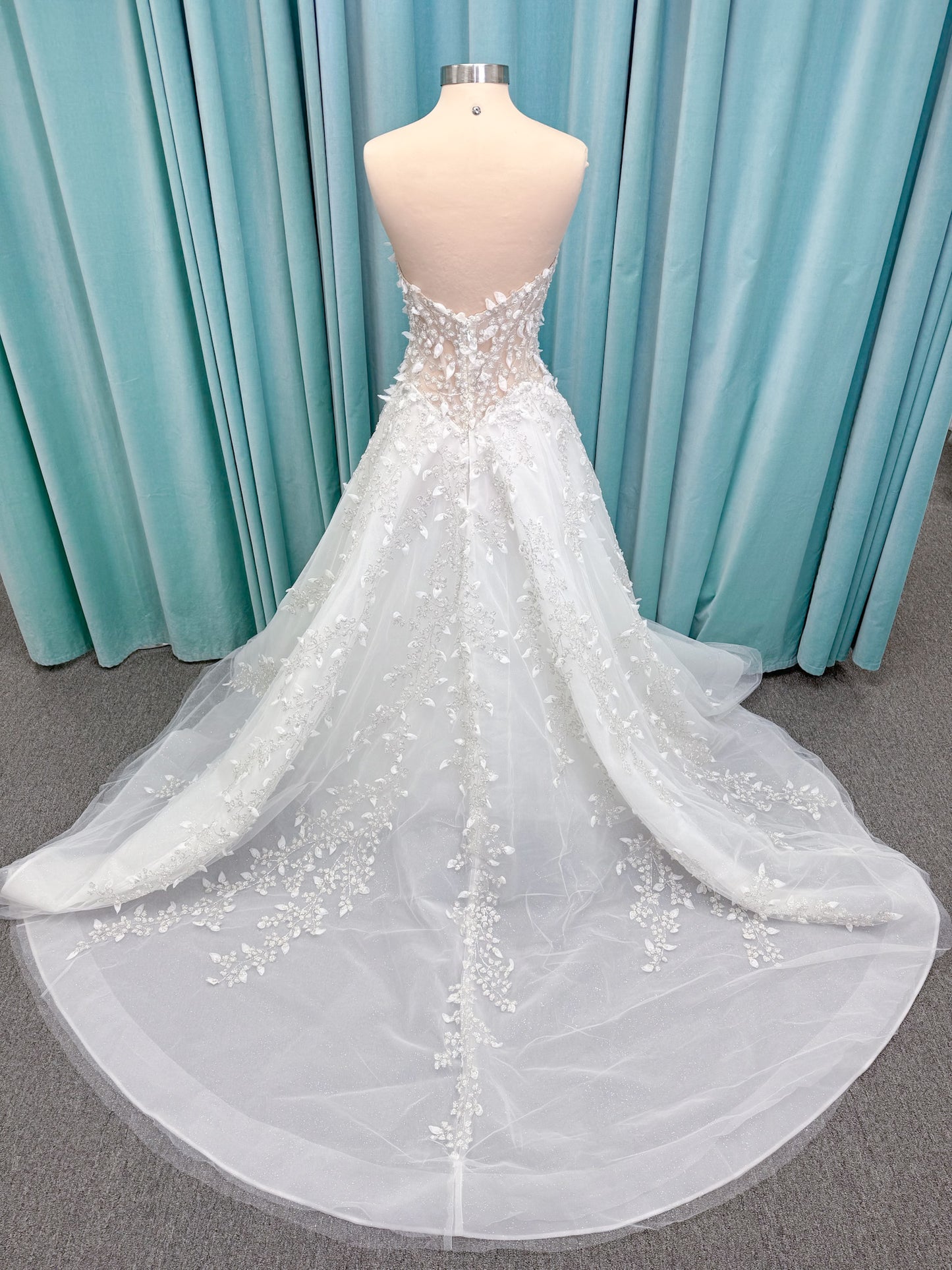 Randy Fenoli Goddess ballgown wedding dress on mannequin with plunging sweetheart neckline, 3D leaf appliqué, basque waist, high skirt slit, and sparkle tulle skirt