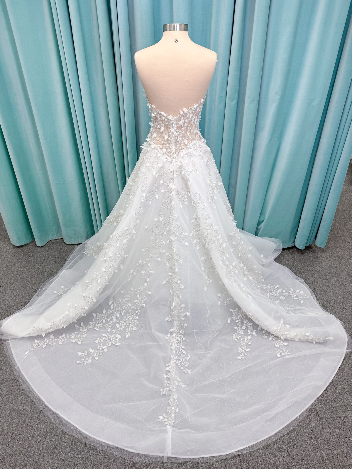 Randy Fenoli Goddess ballgown wedding dress on mannequin with plunging sweetheart neckline, 3D leaf appliqué, basque waist, high skirt slit, and sparkle tulle skirt