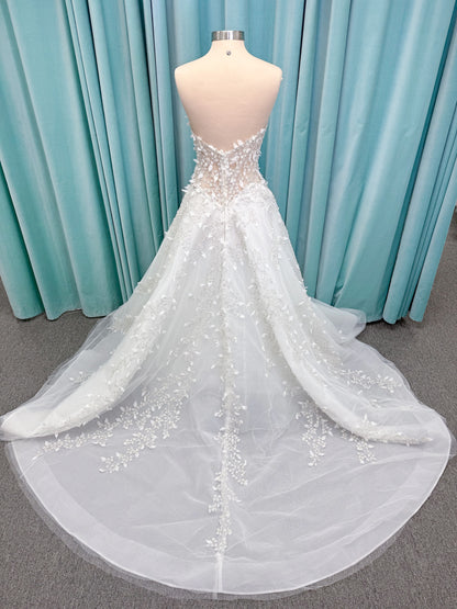 Randy Fenoli Goddess ballgown wedding dress on mannequin with plunging sweetheart neckline, 3D leaf appliqué, basque waist, high skirt slit, and sparkle tulle skirt
