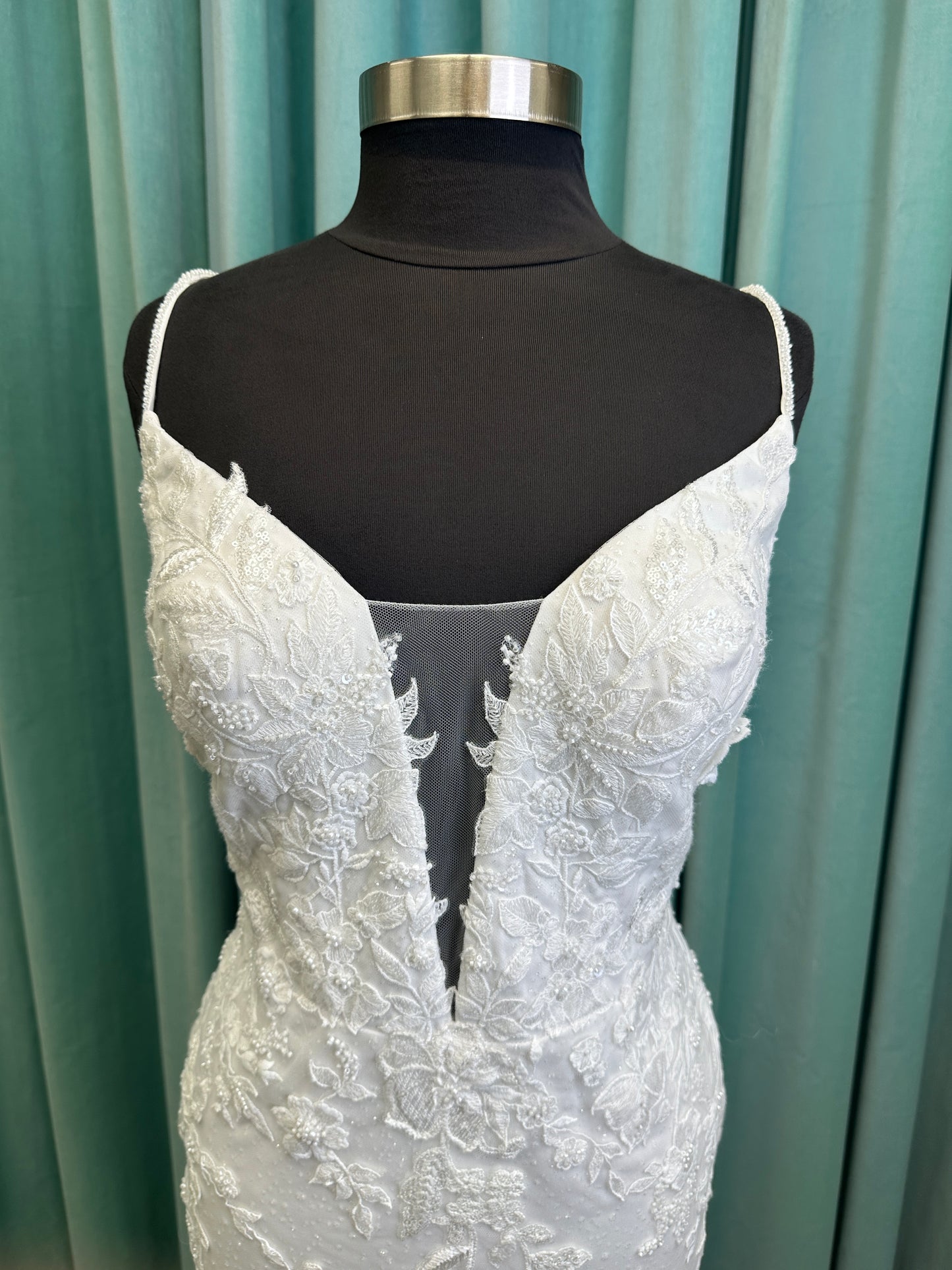 Gracie ivory long sleeve V-neck fit-and-flare wedding dress on mannequin with illusion lace sleeves, fitted silhouette, and scalloped lace cathedral train.
