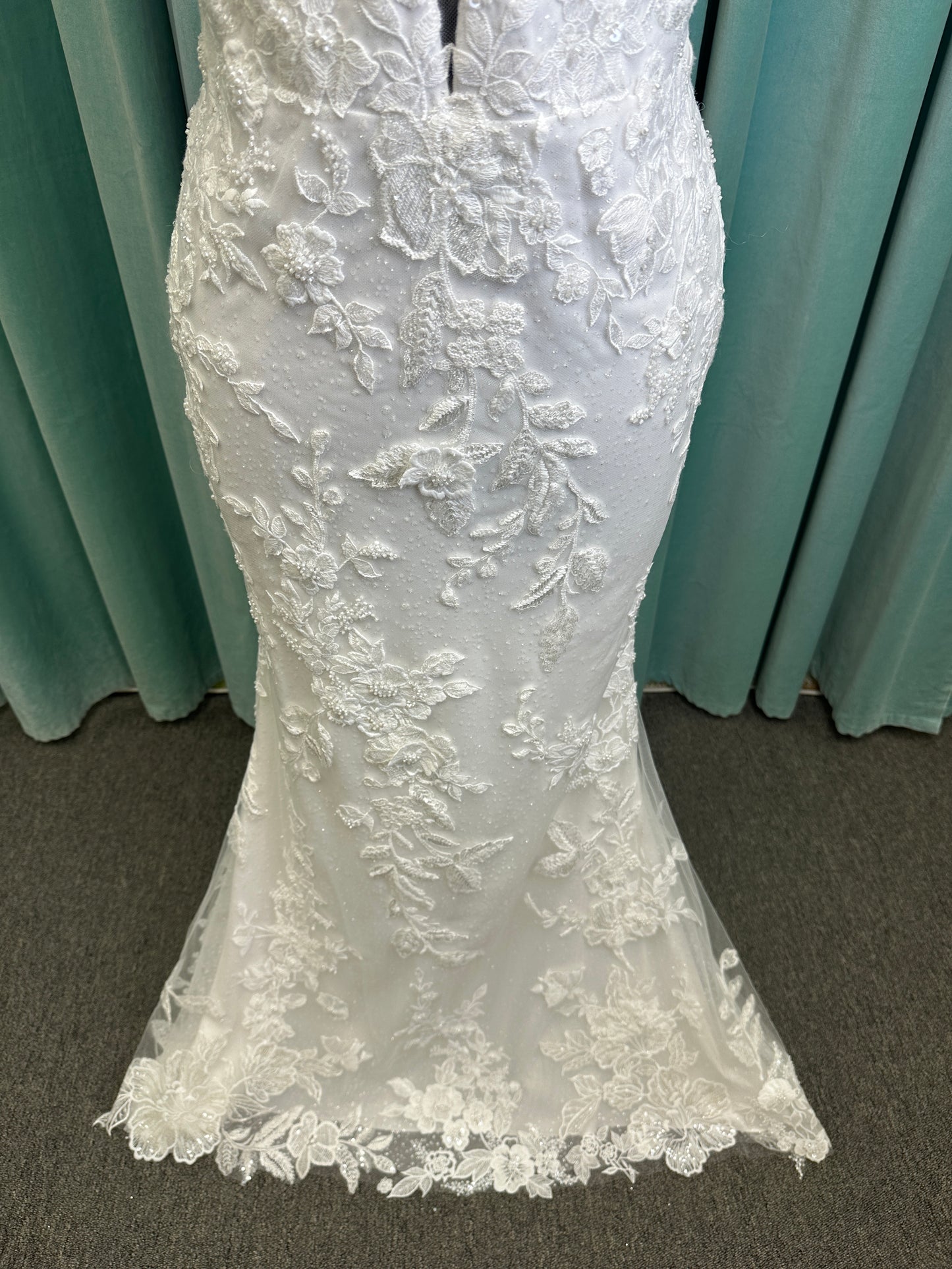 Gracie ivory long sleeve V-neck fit-and-flare wedding dress on mannequin with illusion lace sleeves, fitted silhouette, and scalloped lace cathedral train.
