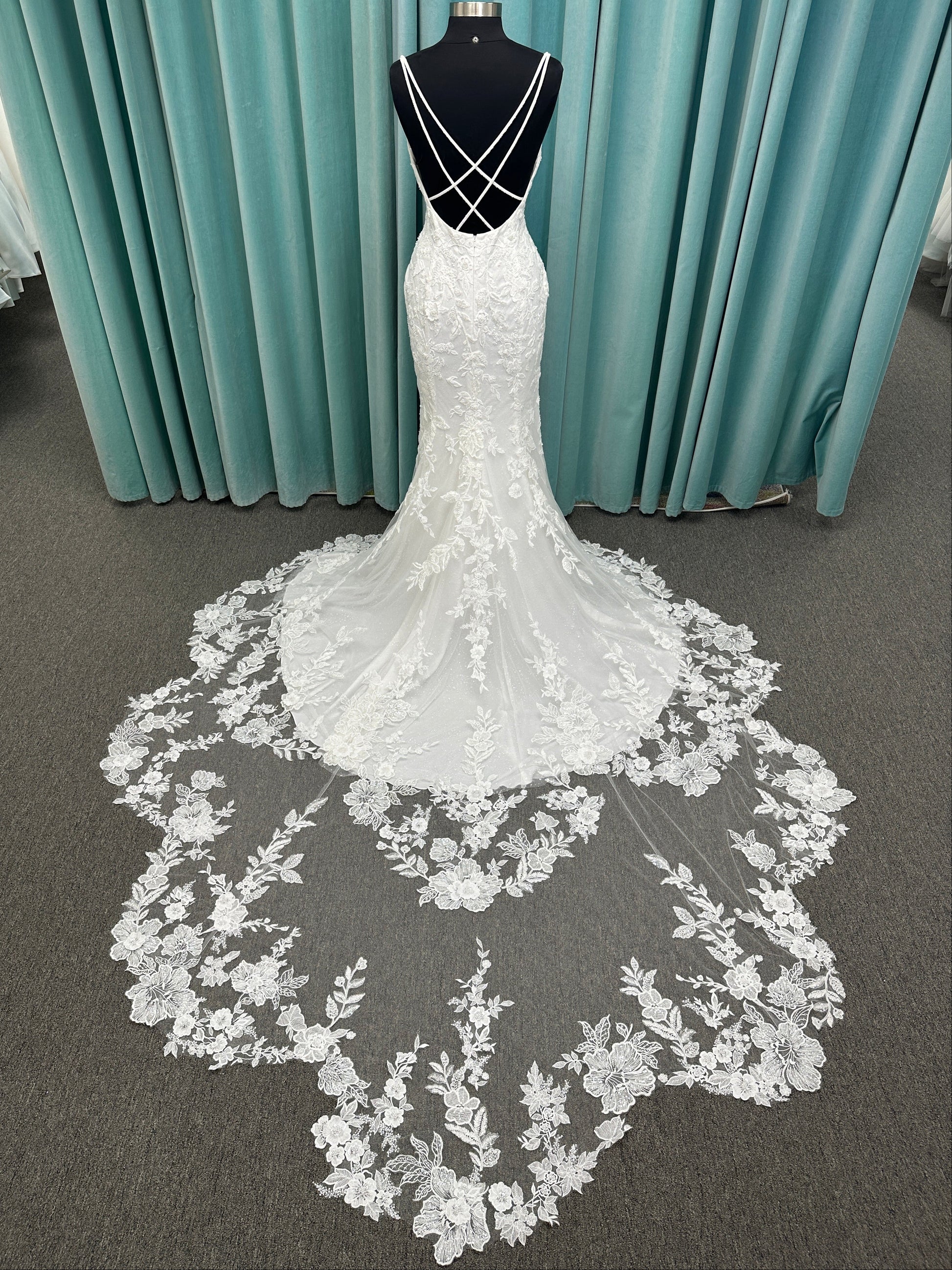 Gracie ivory long sleeve V-neck fit-and-flare wedding dress on mannequin with illusion lace sleeves, fitted silhouette, and scalloped lace cathedral train.
