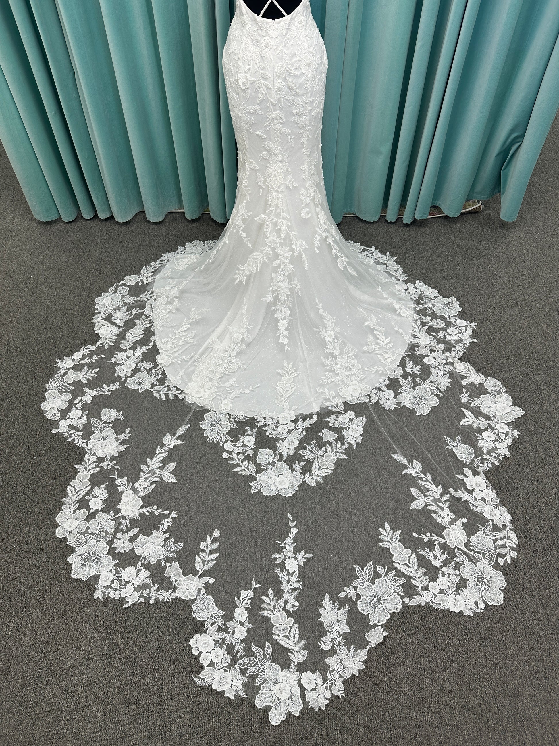 Gracie ivory long sleeve V-neck fit-and-flare wedding dress on mannequin with illusion lace sleeves, fitted silhouette, and scalloped lace cathedral train.
