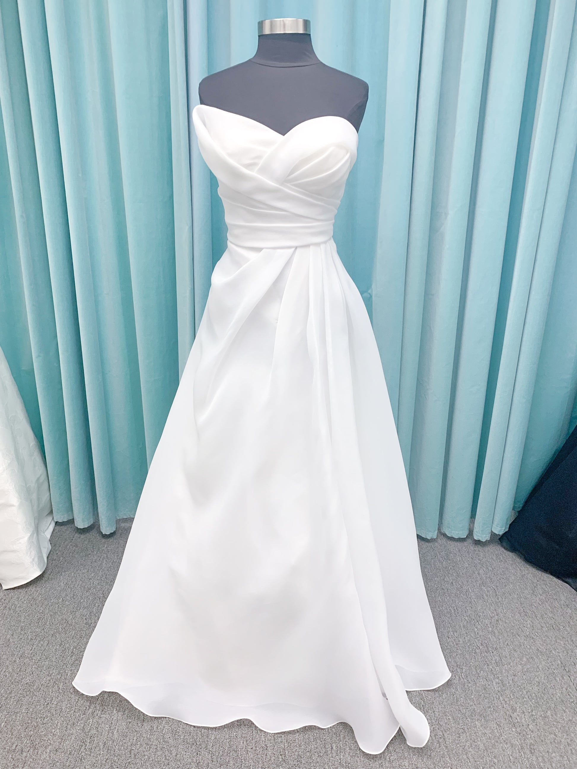 Morilee 2989 Helenia contemporary strapless A-line wedding dress in draped organza with detachable bow and sweeping train.