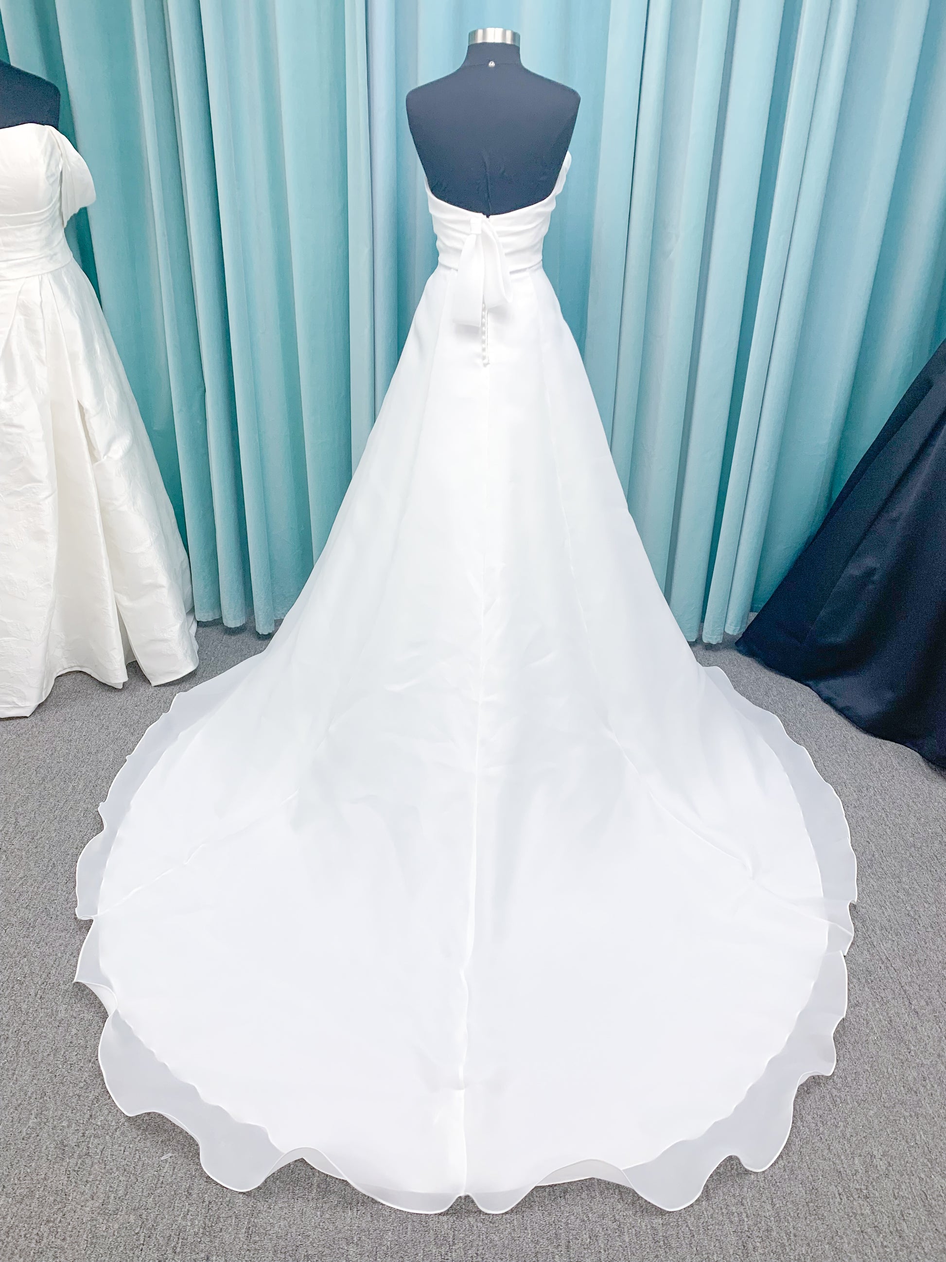 Morilee 2989 Helenia contemporary strapless A-line wedding dress in draped organza with detachable bow and sweeping train.