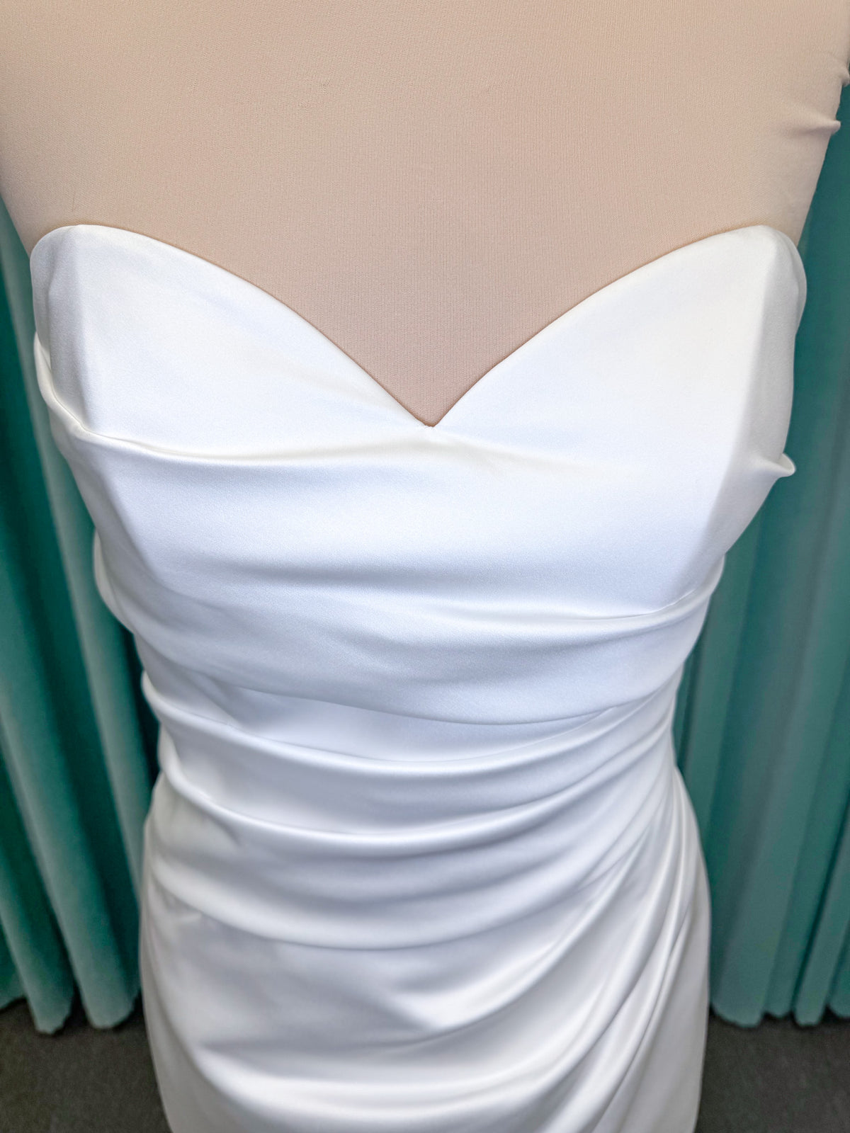Strapless satin fit-and-flare wedding dress with sweetheart neckline, ruched bodice, fitted hips, and flared chapel-length train.