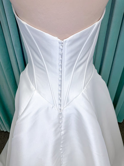 Randy Fenoli Idonna ball gown wedding dress on mannequin with strapless sweetheart neckline, structured mikado bodice, basque waist, covered back buttons, and side pockets