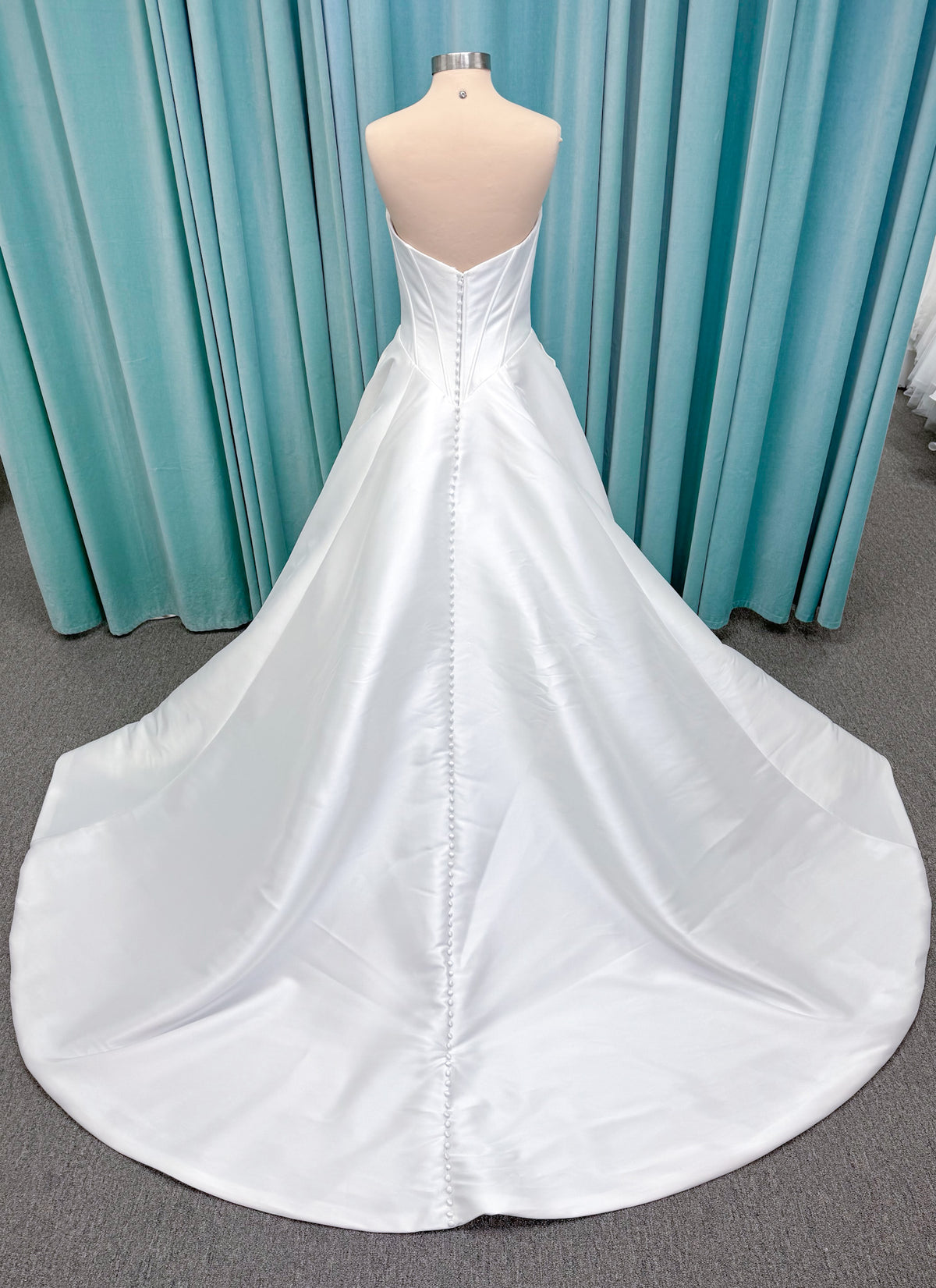 Randy Fenoli Idonna ball gown wedding dress on mannequin with strapless sweetheart neckline, structured mikado bodice, basque waist, covered back buttons, and side pockets