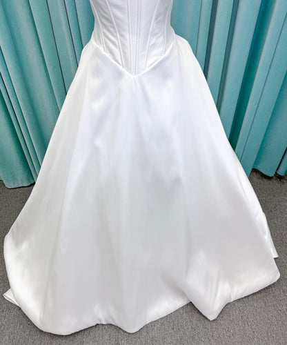 Randy Fenoli Idonna ball gown wedding dress on mannequin with strapless sweetheart neckline, structured mikado bodice, basque waist, covered back buttons, and side pockets