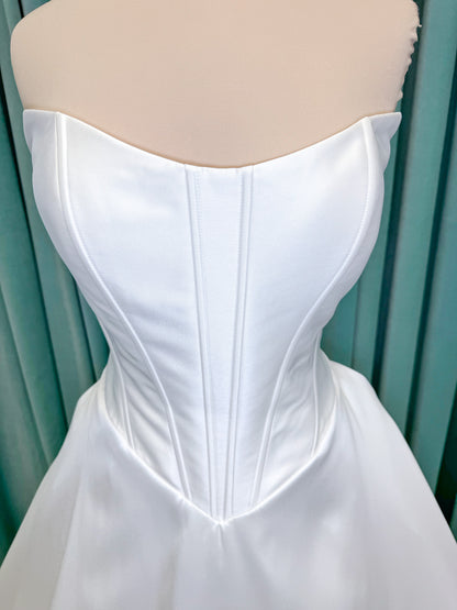 Randy Fenoli Idonna ball gown wedding dress on mannequin with strapless sweetheart neckline, structured mikado bodice, basque waist, covered back buttons, and side pockets