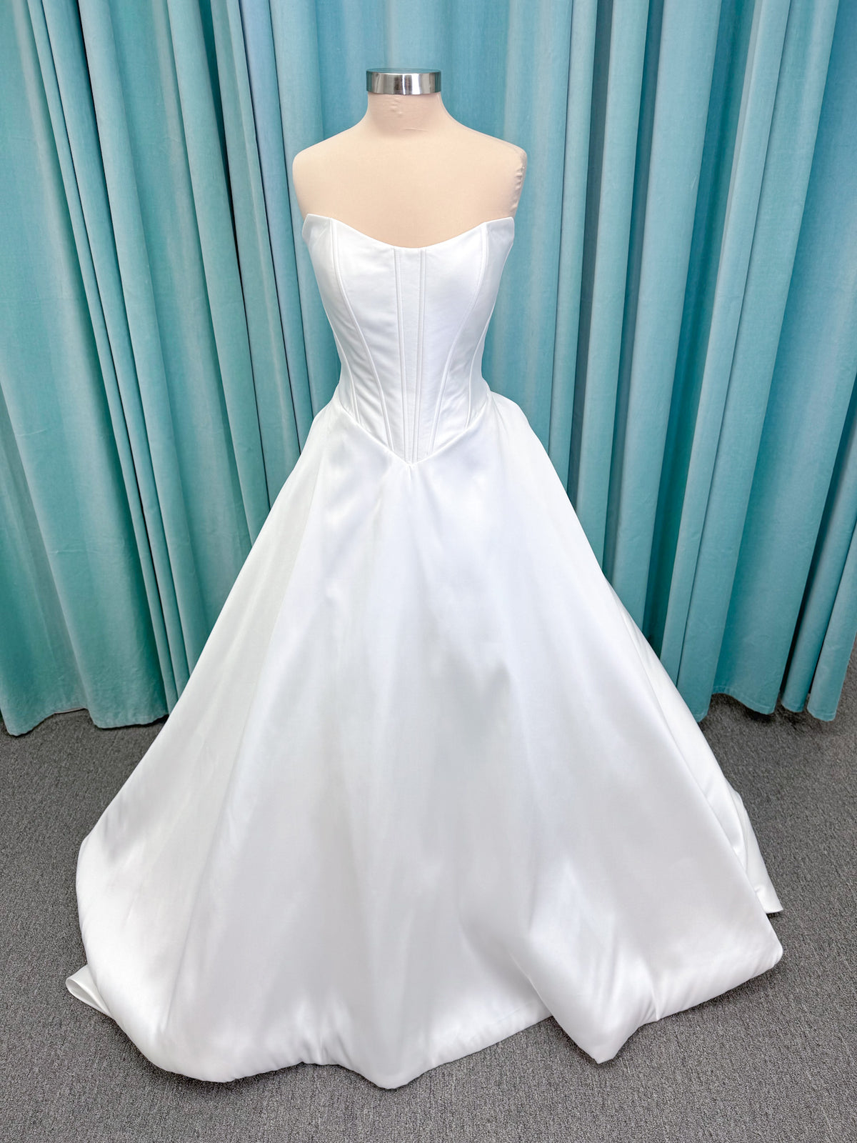 Randy Fenoli Idonna ball gown wedding dress on mannequin with strapless sweetheart neckline, structured mikado bodice, basque waist, covered back buttons, and side pockets