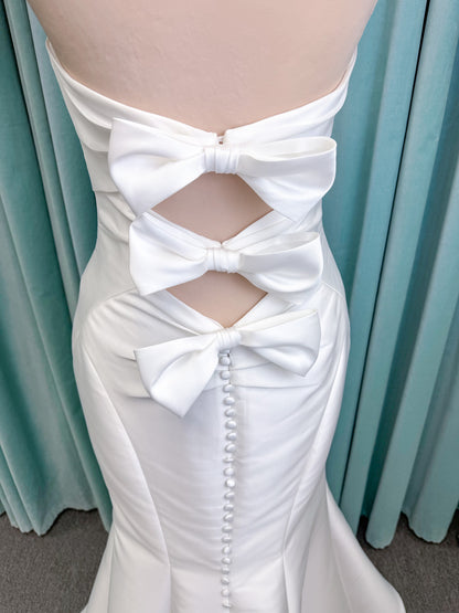Randy Fenoli Imani fit and flare wedding dress on mannequin with strapless sweetheart neckline, structured mikado bodice, and oversized back bow with covered buttons