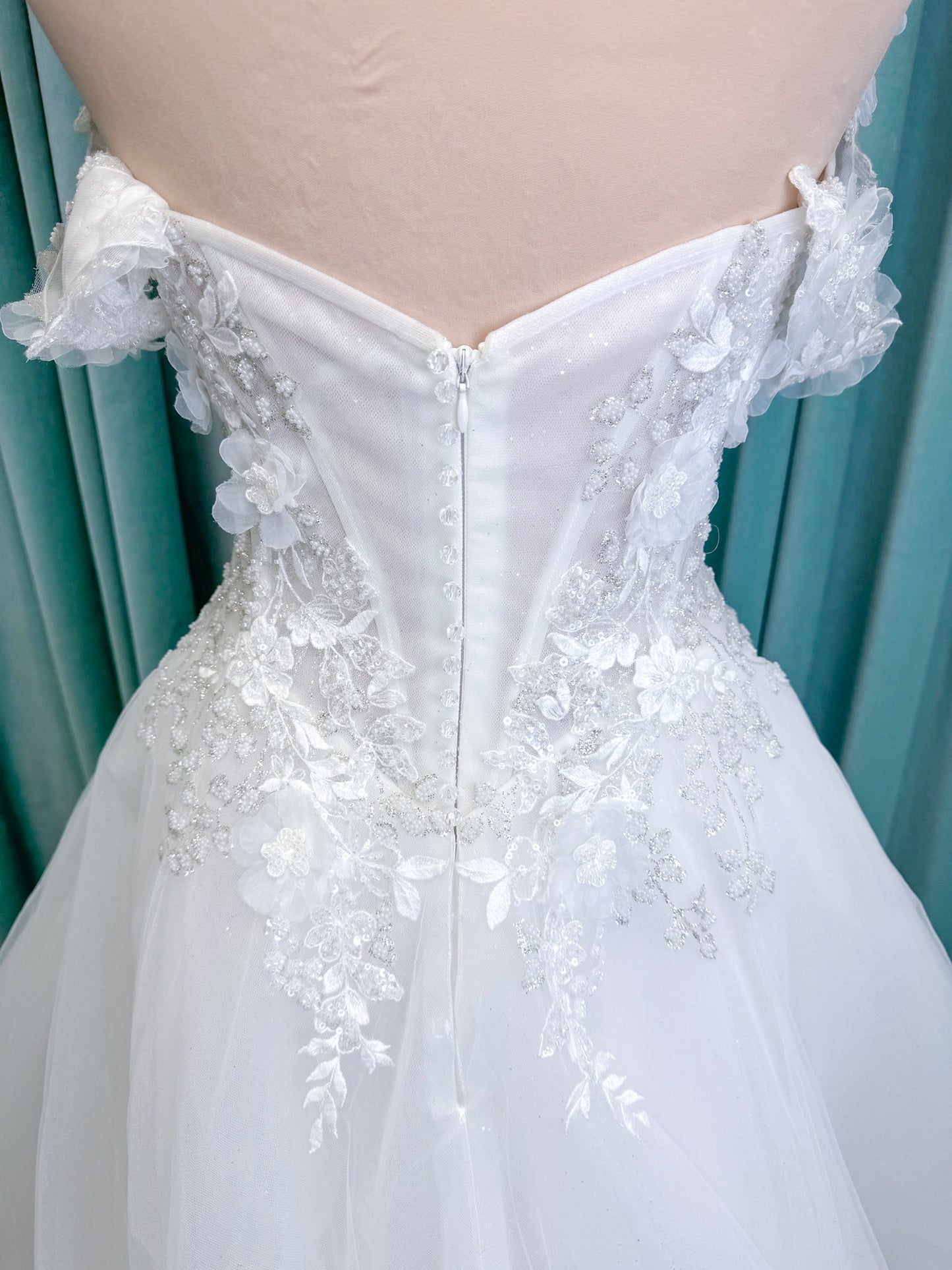 Randy Fenoli Indy A-line wedding dress on mannequin with off-the-shoulder sleeve drape, strapless sweetheart bodice, lace appliqué, basque waist, and high skirt slit