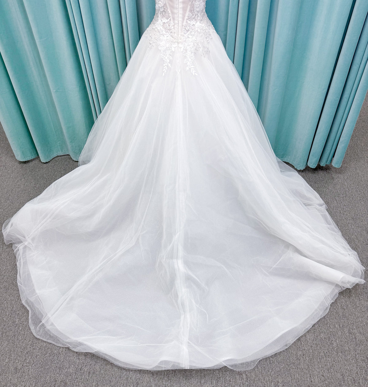 Randy Fenoli Indy A-line wedding dress on mannequin with off-the-shoulder sleeve drape, strapless sweetheart bodice, lace appliqué, basque waist, and high skirt slit