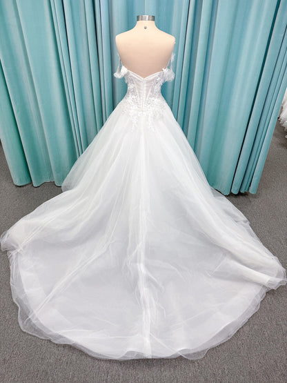 Randy Fenoli Indy A-line wedding dress on mannequin with off-the-shoulder sleeve drape, strapless sweetheart bodice, lace appliqué, basque waist, and high skirt slit