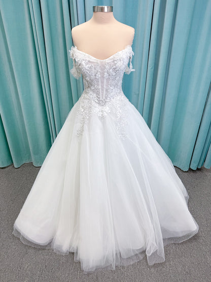 Randy Fenoli Indy A-line wedding dress on mannequin with off-the-shoulder sleeve drape, strapless sweetheart bodice, lace appliqué, basque waist, and high skirt slit