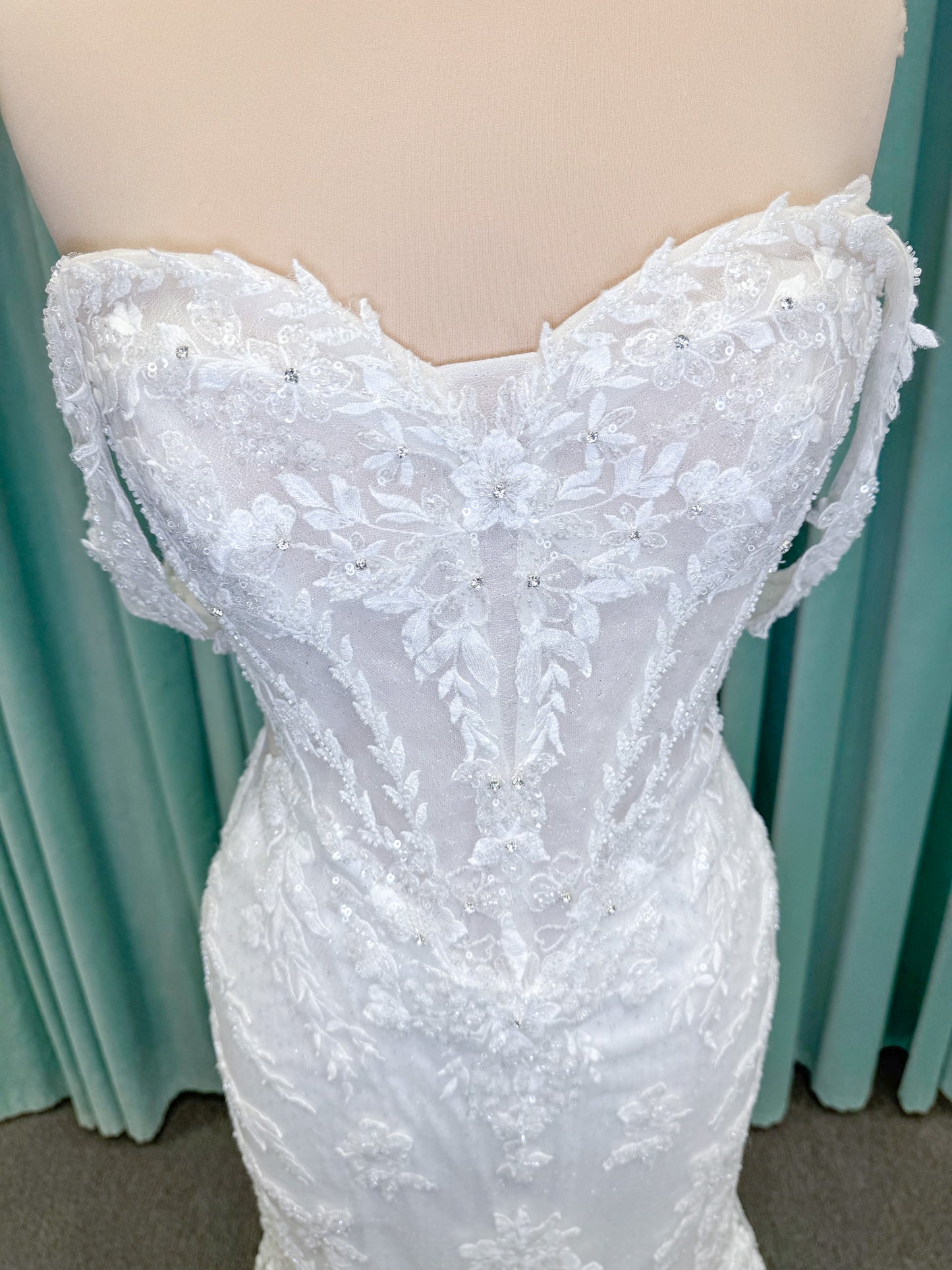 Randy Fenoli Jillian fit and flare wedding dress on mannequin with strapless sweetheart neckline, beaded lace appliqué, detachable off-the-shoulder straps, and glitter tulle skirt