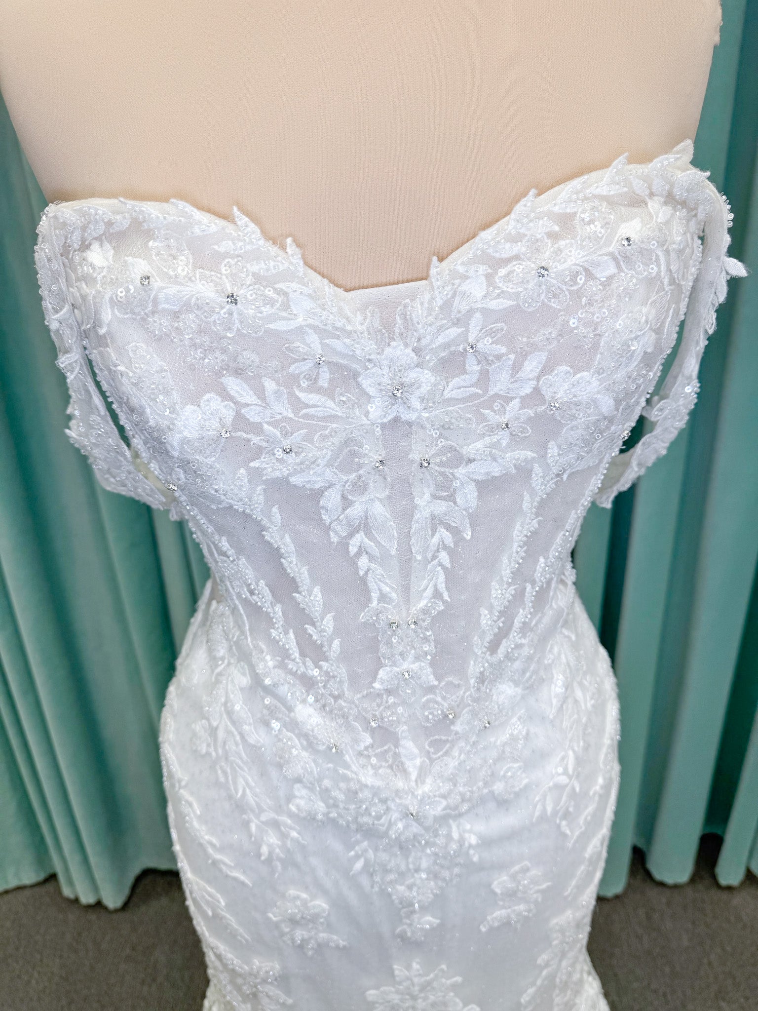 Randy Fenoli Jillian fit and flare wedding dress on mannequin with strapless sweetheart neckline, beaded lace appliqué, detachable off-the-shoulder straps, and glitter tulle skirt