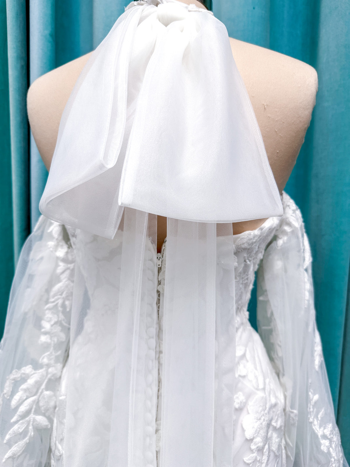 Morilee 2936 Kali fit and flare wedding dress on mannequin with high neckline, threadwork floral appliqued tulle, and detachable organza bow blouson sleeves