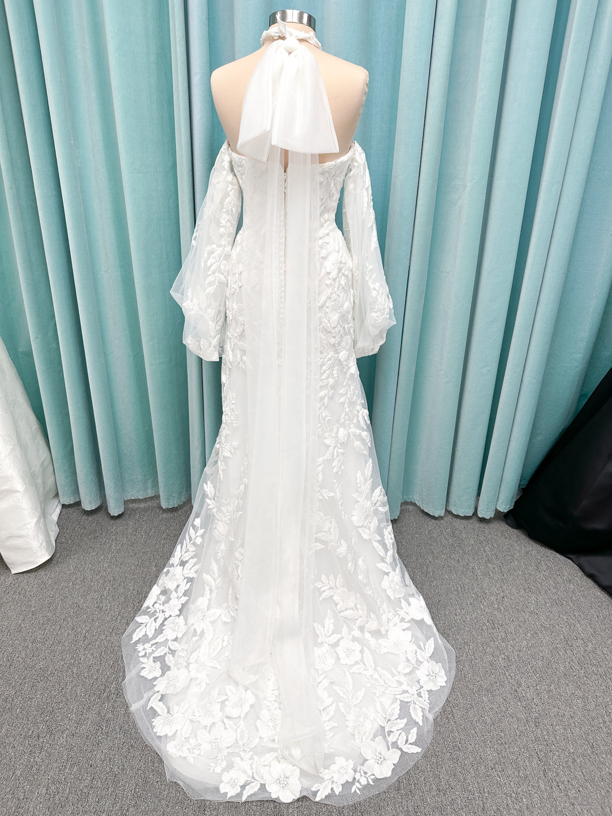 Morilee 2936 Kali fit and flare wedding dress on mannequin with high neckline, threadwork floral appliqued tulle, and detachable organza bow blouson sleeves