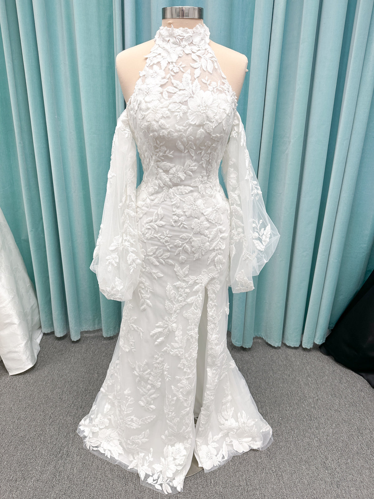 Morilee 2936 Kali fit and flare wedding dress on mannequin with high neckline, threadwork floral appliqued tulle, and detachable organza bow blouson sleeves