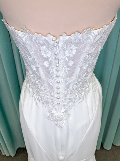 Randy Fenoli Kitty fit and flare wedding dress on mannequin with strapless sweetheart neckline, floral lace appliqué, and fluid crepe skirt