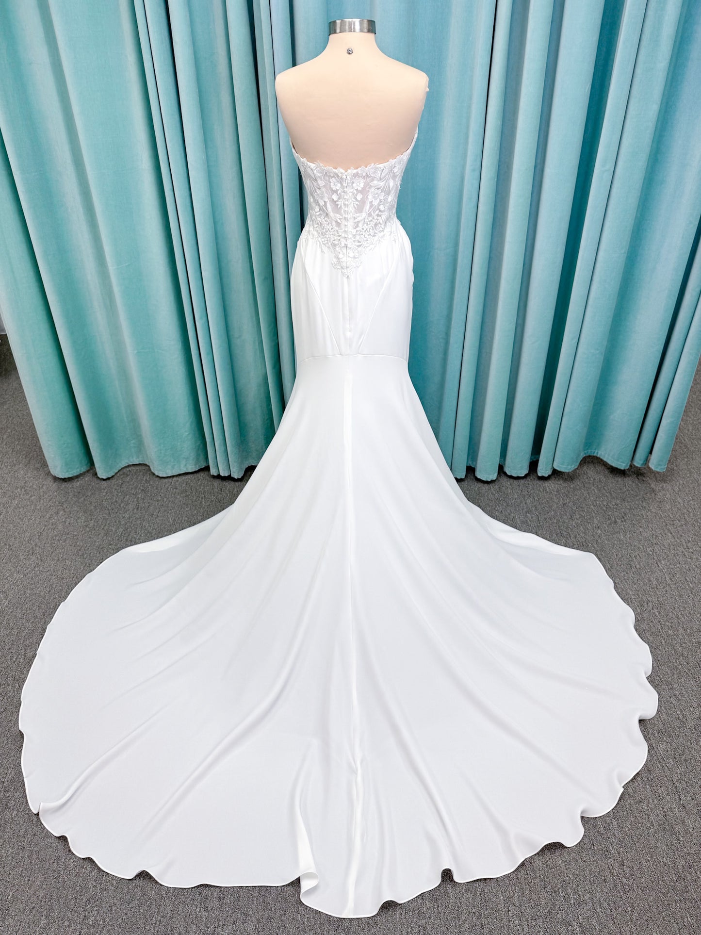 Randy Fenoli Kitty fit and flare wedding dress on mannequin with strapless sweetheart neckline, floral lace appliqué, and fluid crepe skirt
