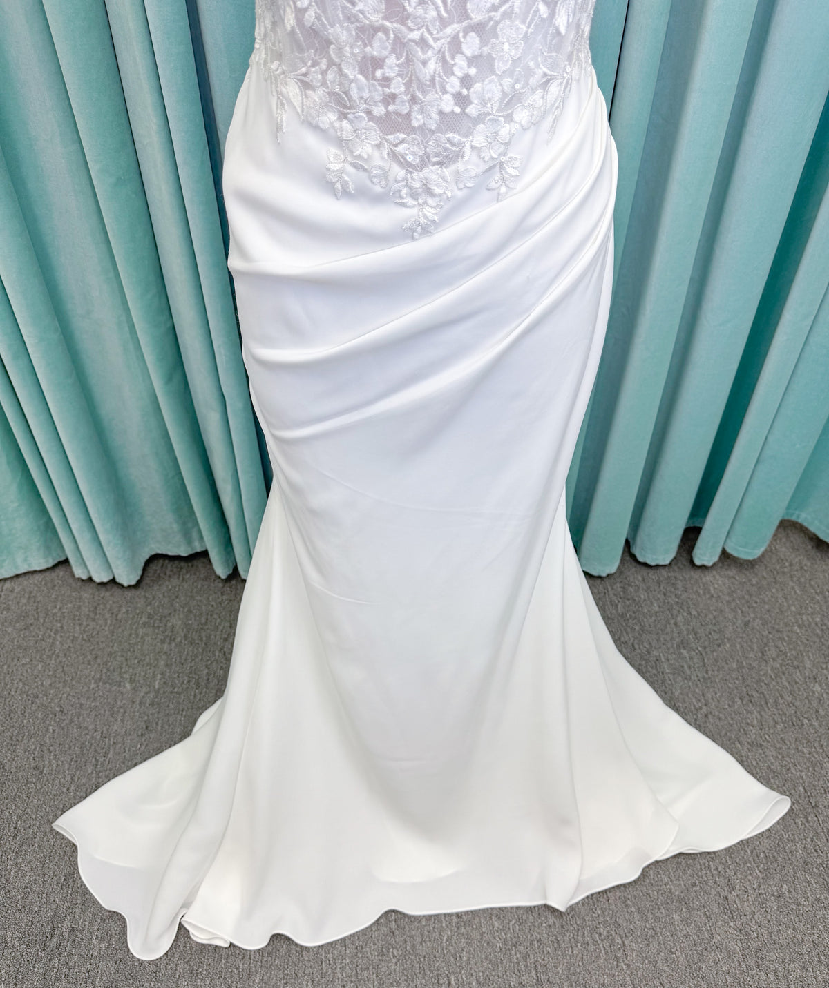 Randy Fenoli Kitty fit and flare wedding dress on mannequin with strapless sweetheart neckline, floral lace appliqué, and fluid crepe skirt