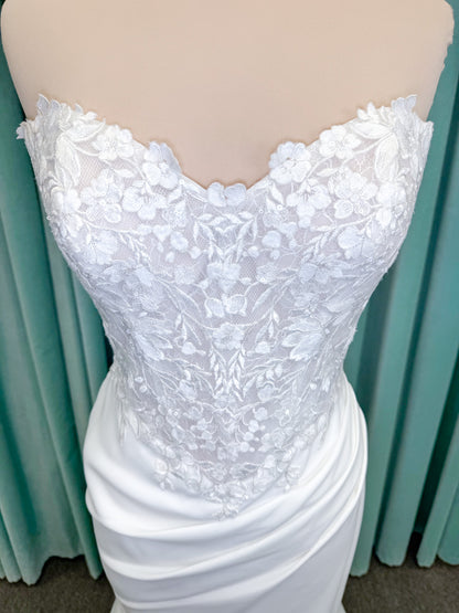 Randy Fenoli Kitty fit and flare wedding dress on mannequin with strapless sweetheart neckline, floral lace appliqué, and fluid crepe skirt