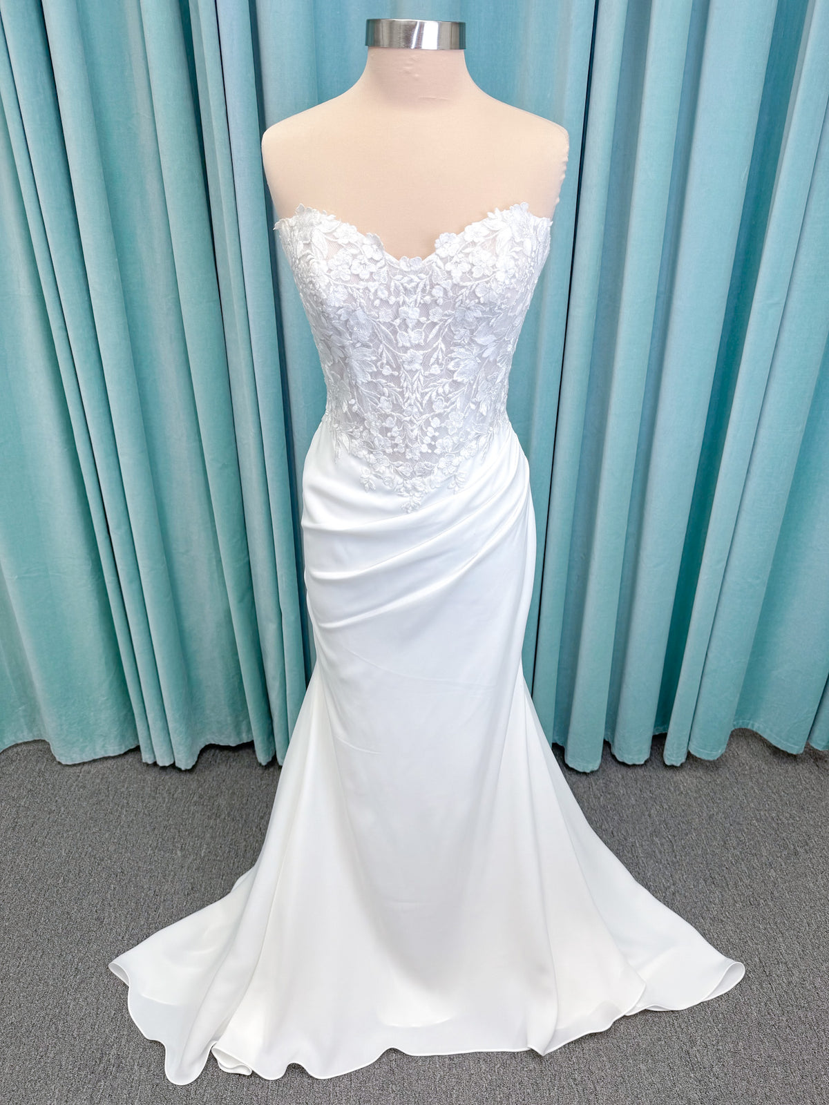 Randy Fenoli Kitty fit and flare wedding dress on mannequin with strapless sweetheart neckline, floral lace appliqué, and fluid crepe skirt
