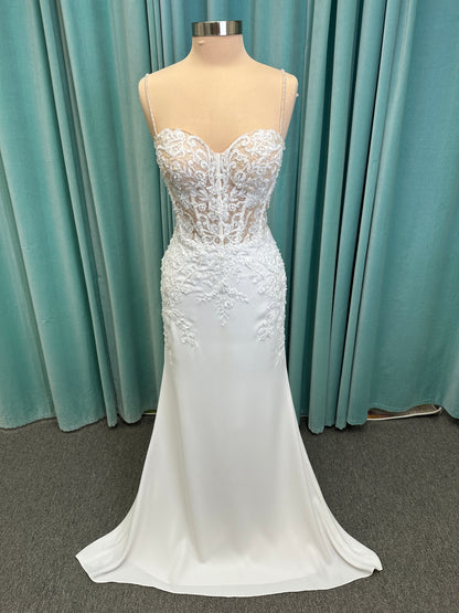 Liena ivory spaghetti strap wedding dress on mannequin with illusion corset bodice, floral lace appliqués, sweetheart neckline, and crepe skirt.
