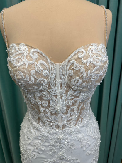 Liena ivory spaghetti strap wedding dress on mannequin with illusion corset bodice, floral lace appliqués, sweetheart neckline, and crepe skirt.
