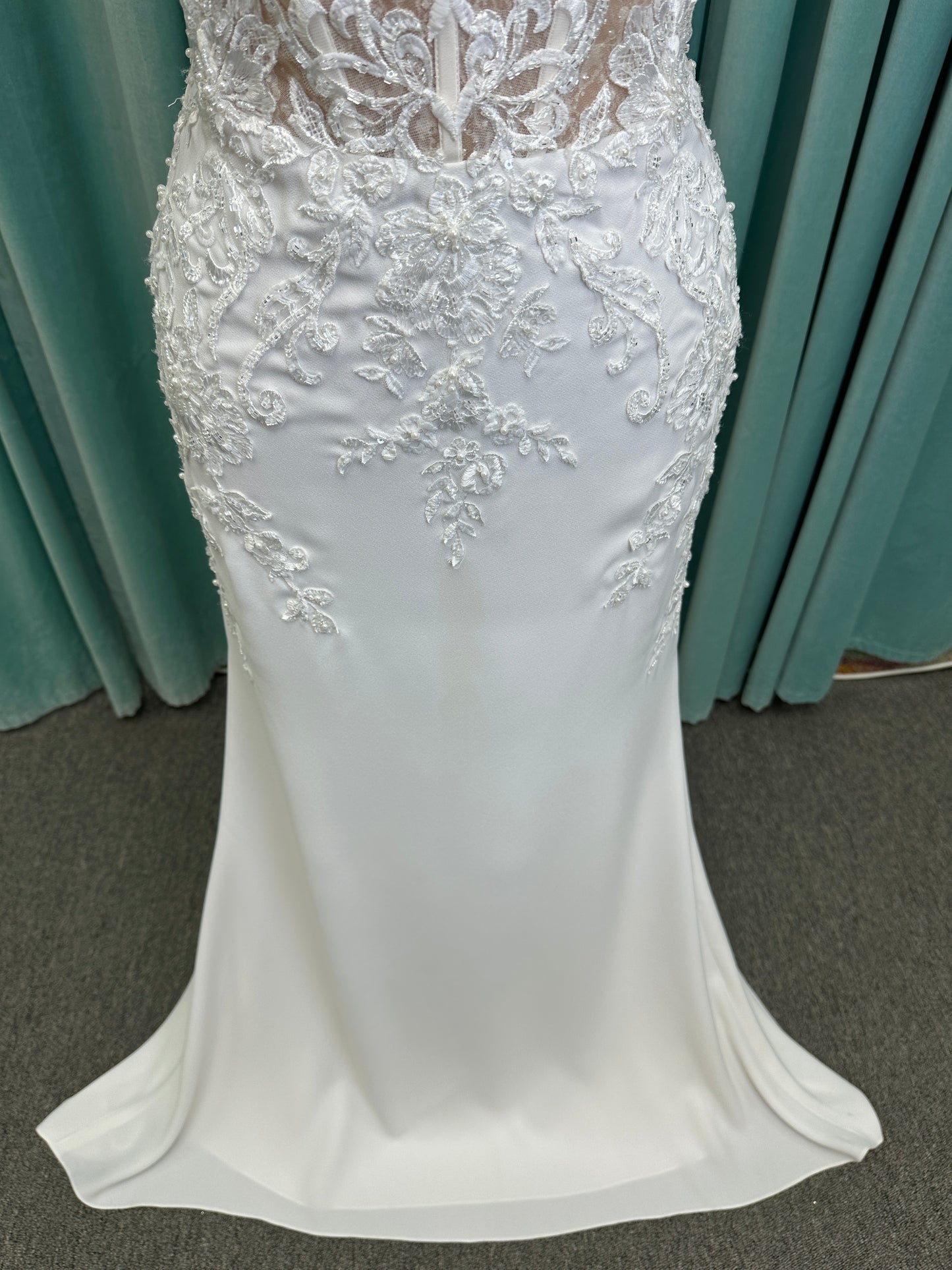 Liena ivory spaghetti strap wedding dress on mannequin with illusion corset bodice, floral lace appliqués, sweetheart neckline, and crepe skirt.
