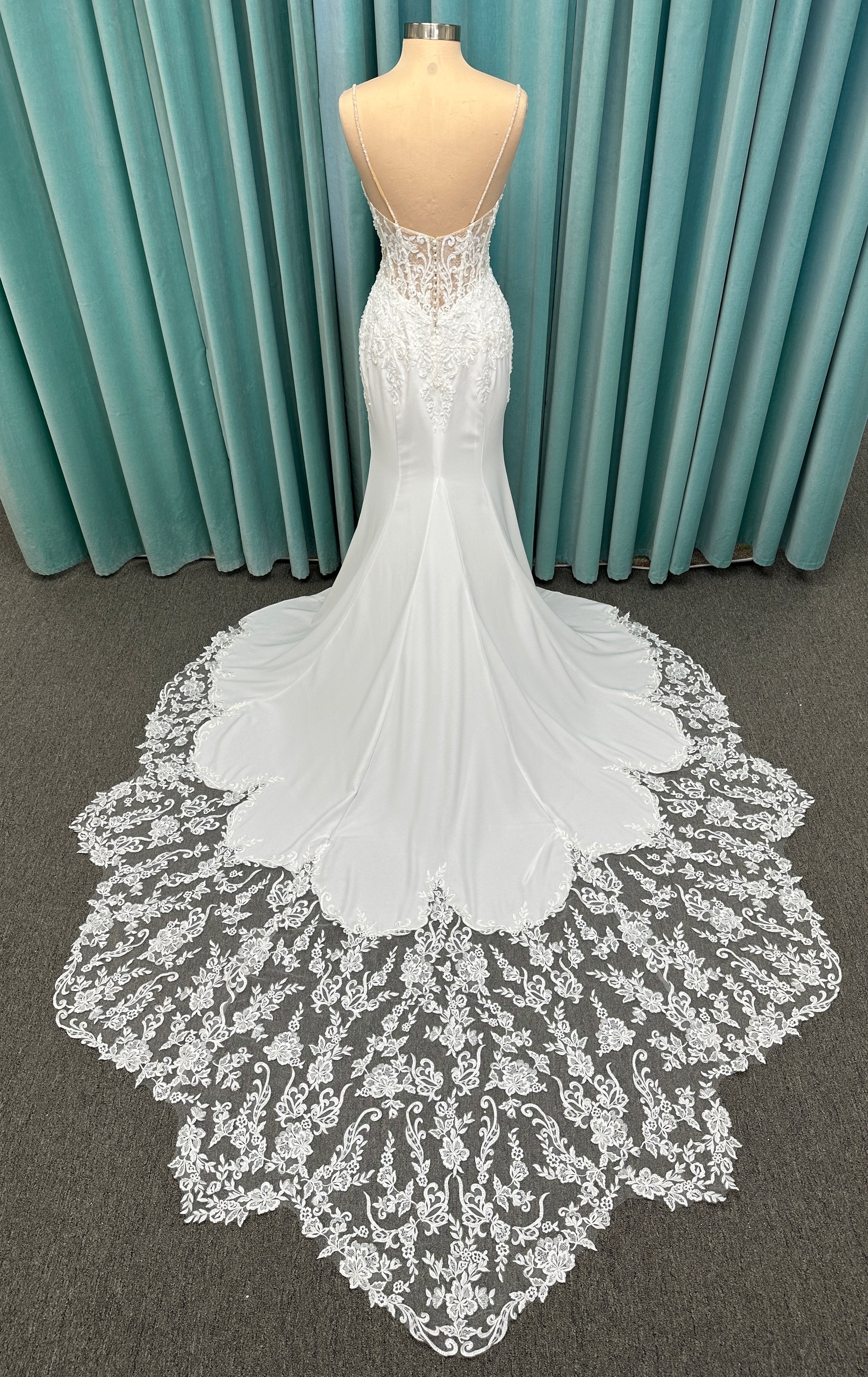 Liena ivory spaghetti strap wedding dress on mannequin with illusion corset bodice, floral lace appliqués, sweetheart neckline, and crepe skirt.
