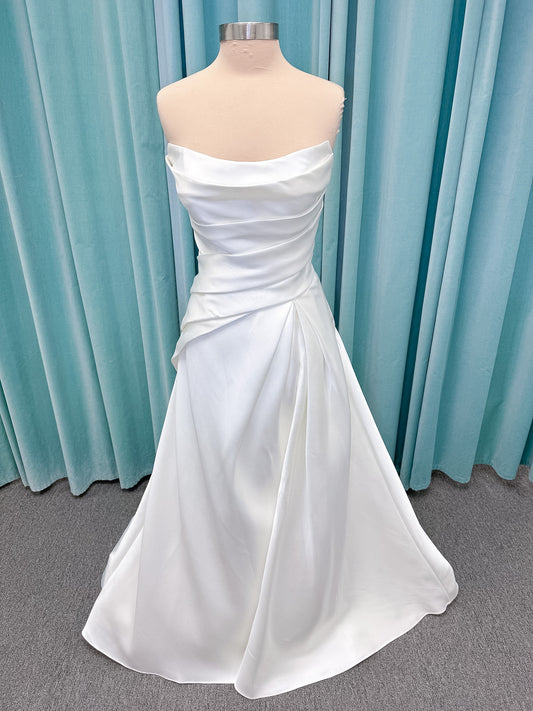 Moonlight Bridal J6978 Livana A-line wedding dress on mannequin with strapless scoop neckline, ruched mikado bodice, asymmetrical draped waist, high front slit, and chapel train