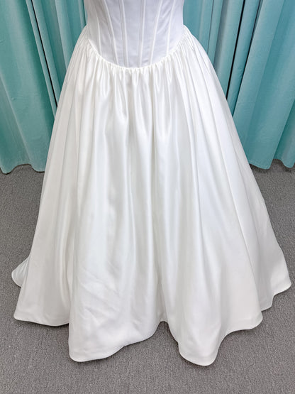 Moonlight Bridal J6953 Luna A-line wedding dress on mannequin with straight draped satin neckline, pleated off-the-shoulder swag sleeves, boned basque waist, full rouched satin skirt, and sweep train