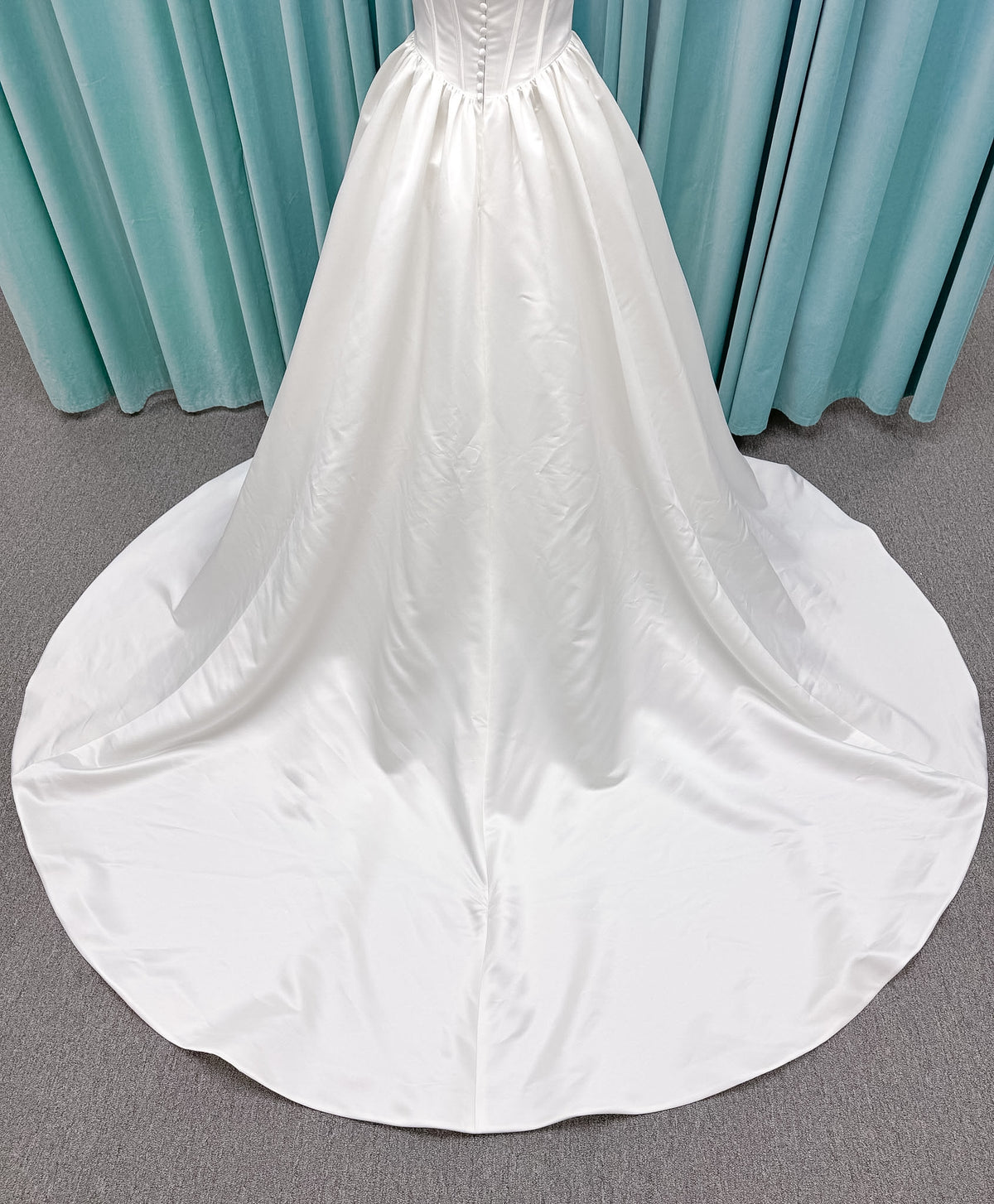 Moonlight Bridal J6953 Luna A-line wedding dress on mannequin with straight draped satin neckline, pleated off-the-shoulder swag sleeves, boned basque waist, full rouched satin skirt, and sweep train