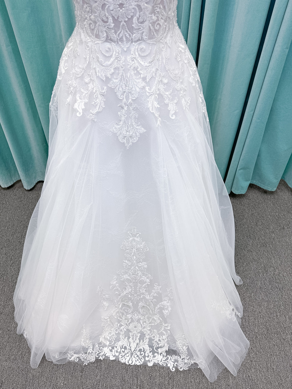 Moonlight Bridal J6972 Lunetta A-line wedding dress on mannequin with strapless soft sweetheart neckline, beaded lace appliques over tulle and Chantilly lace, drop waist, and scalloped applique sweep train