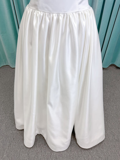 Moonlight Bridal J6956 Mahina ballgown wedding dress on mannequin with scoop neckline, detachable off-the-shoulder swag sleeves, drop waist, ruched shimmering satin skirt, and chapel train with horsehair hem