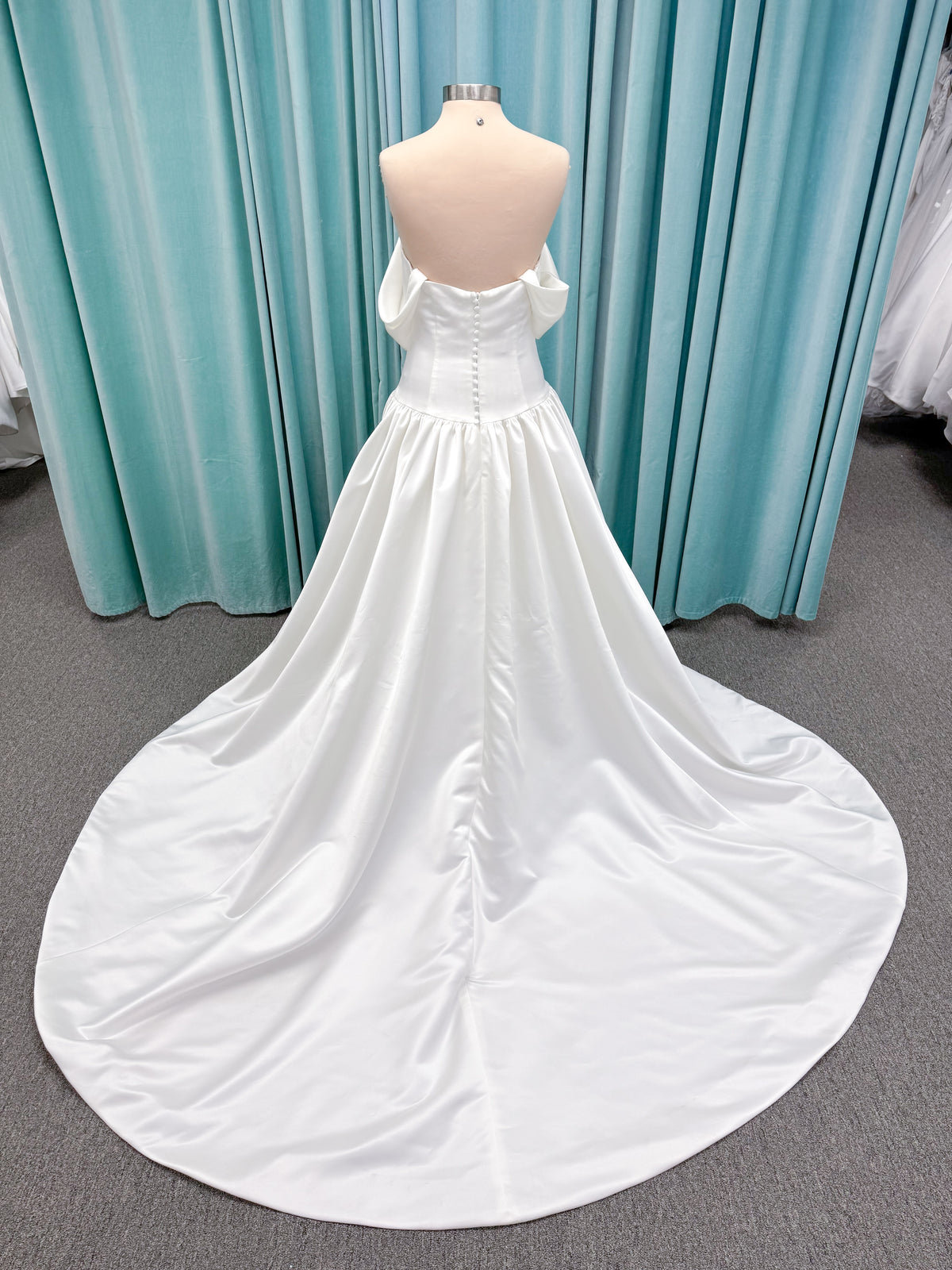 Moonlight Bridal J6956 Mahina ballgown wedding dress on mannequin with scoop neckline, detachable off-the-shoulder swag sleeves, drop waist, ruched shimmering satin skirt, and chapel train with horsehair hem