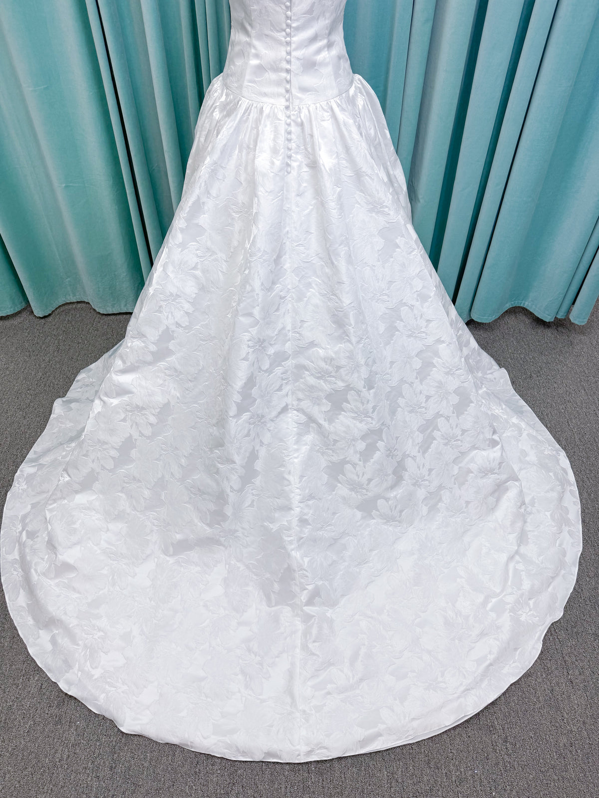 Moonlight Bridal J6994 Marama ballgown wedding dress on mannequin with strapless scoop neckline, textured satin jacquard, fitted drop-waist bodice, detachable short bow sleeves, full skirt, and sweep train