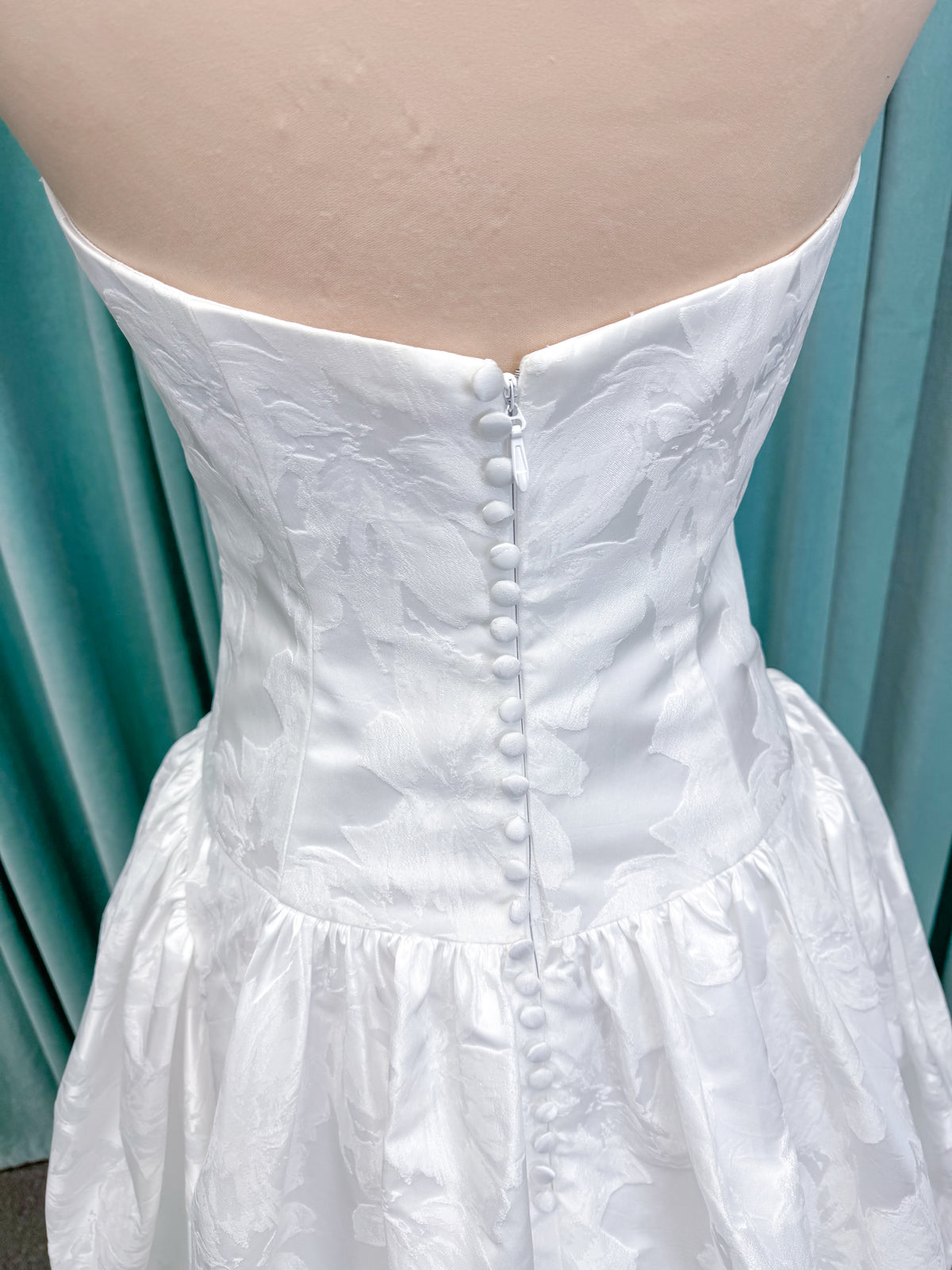 Moonlight Bridal J6994 Marama ballgown wedding dress on mannequin with strapless scoop neckline, textured satin jacquard, fitted drop-waist bodice, detachable short bow sleeves, full skirt, and sweep train