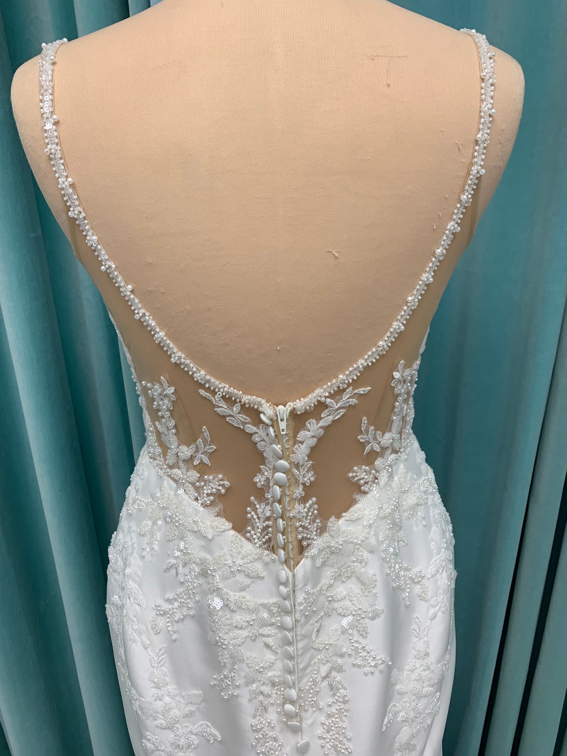 Marjorie ivory spaghetti strap wedding dress on mannequin with illusion corset bodice, floral lace appliqués, and scoop neckline.
