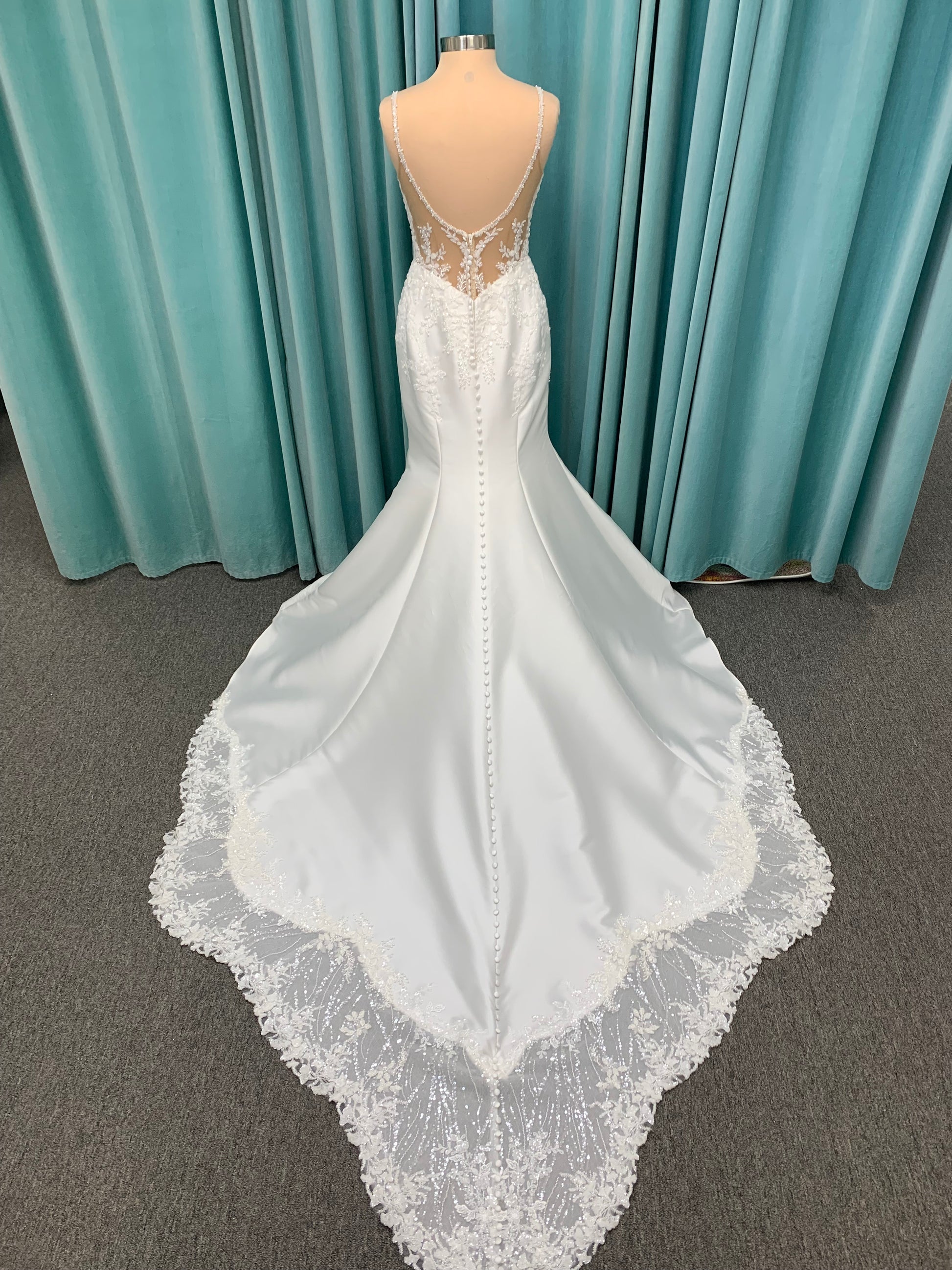 Marjorie ivory spaghetti strap wedding dress on mannequin with illusion corset bodice, floral lace appliqués, and scoop neckline.
