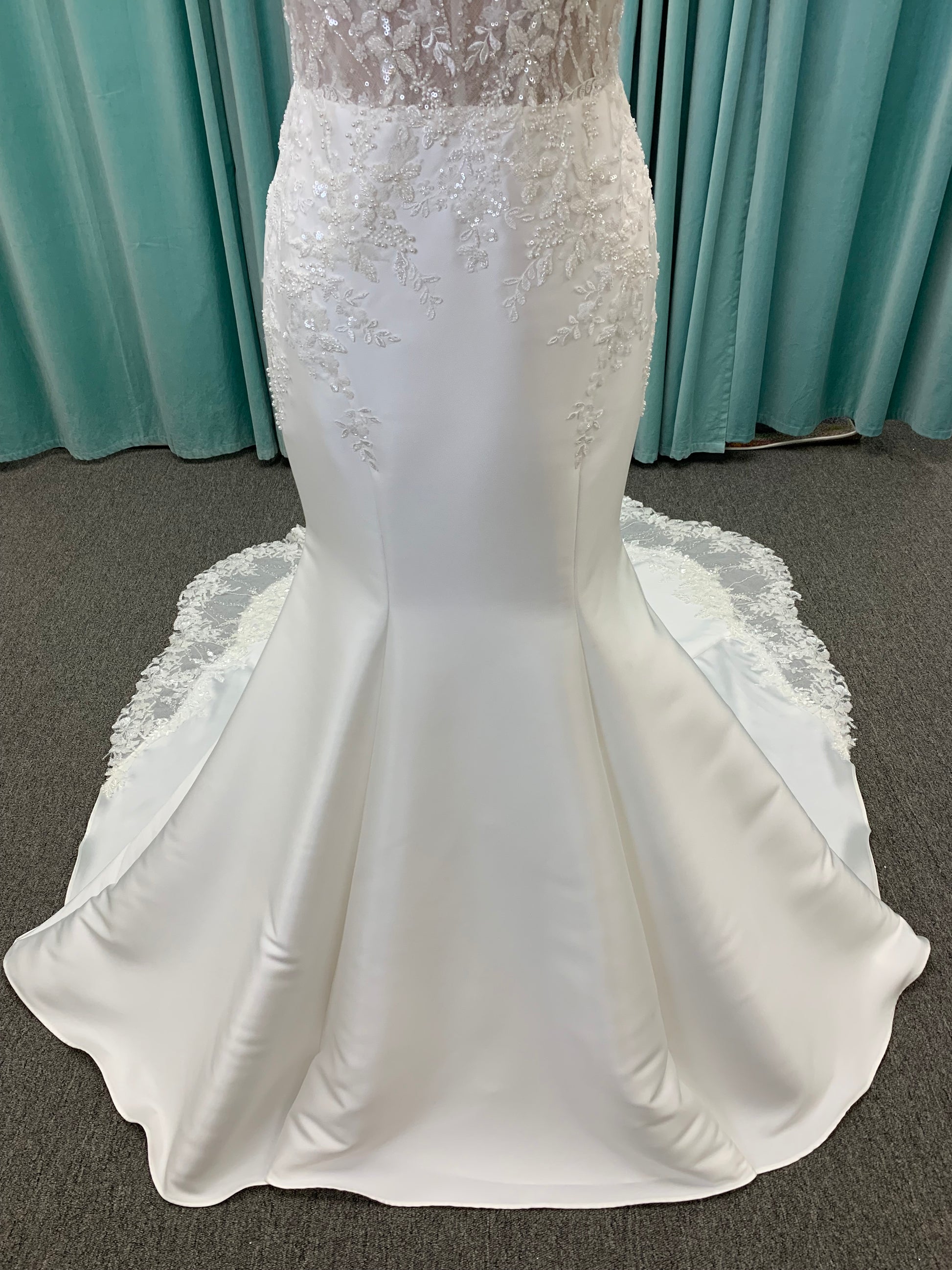 Marjorie ivory spaghetti strap wedding dress on mannequin with illusion corset bodice, floral lace appliqués, and scoop neckline.
